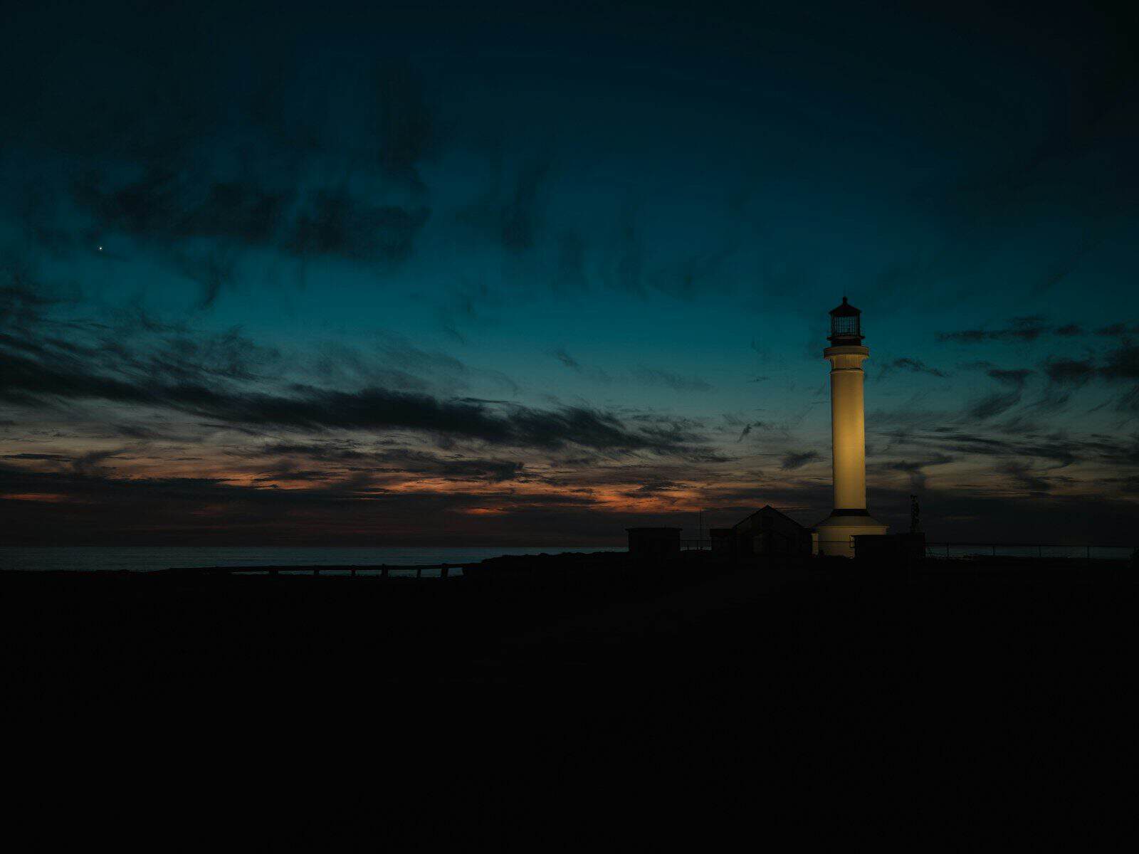 Lighthouse illuminated against a dark twilight sky